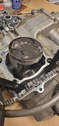 Piston crown damaged by debris, found during teardown