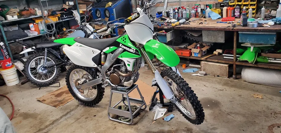 Finished green and white Kawasaki dirt bike in the shop